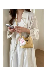 Chic yellow leather bucket bag featuring a secure metal turn-lock and cute plush bunny charm.