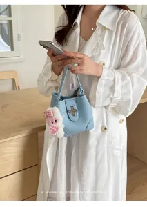 Stylish light blue leather bucket bag with metal lock and cute plush rabbit keychain.