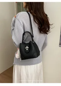 Detail shot of a sleek black bucket bag with silver lock and shoulder strap, back view.