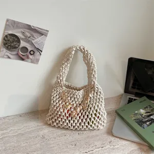 Gedetailleerde close-up van een beige geweven handtas met schelpbedels voor het strand.