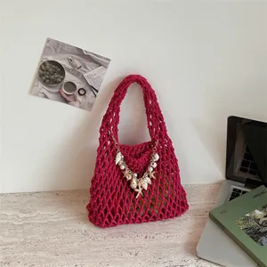 Gedetailleerd overzicht van de roze gehaakte opengewerkte handtas met schelp parel decoratieve ketting.