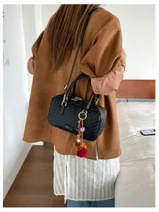 Detailaufnahme der schwarzen geflochtenen Damen Boston Umhängetasche mit feiner Textur und Anhänger.