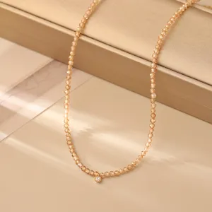 Primo piano di una collana di perline sfaccettate champagne scintillante con ciondolo.