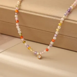Primo piano di una collana di perline sfaccettate colorate con ciondolo in zircone.