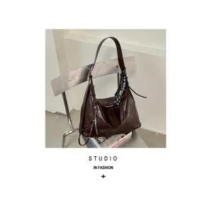 Detailansicht einer braunen Ledertasche hängend an einem modernen Metallstuhl im Studio.