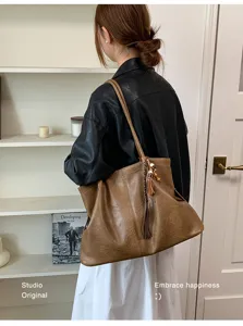 Detailansicht der braunen Retro Schultertasche mit Quastenanhänger, Alltag Pendeln Szene.