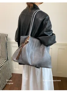 Detailansicht der grauen Schulter-Tasche mit stilvollem Quasten-Anhänger für Damen.