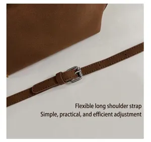 Nahaufnahme des braunen Wildleder-Handtaschen-Schulterriemens mit verstellbarer Metallschnalle.