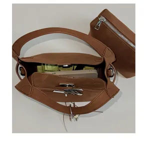 Detailansicht des braunen Handtascheninnenraums mit Metallverschluss und kleinem Beutel.