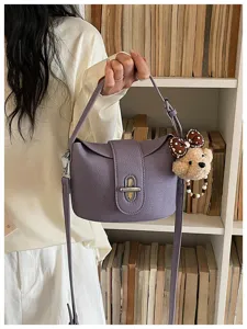 Purple leather bucket bag for women with metal lock closure and cute bear pendant charm.