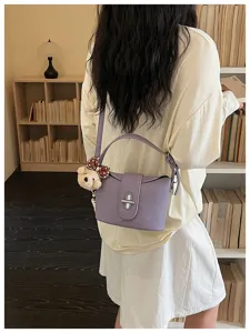 Purple lychee pattern bucket bag with cute bear pendant, stylish crossbody commute handbag.