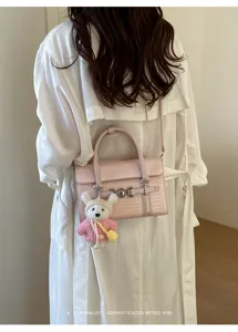 Schicke rosa geflochtene Umhängetasche Detail mit süßem Plüschbär Anhänger im Retrostil.