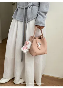 Pink Litchi Grain Bucket Handbag Detail Featuring Chic Metal Lock and Cute Plush Pendant.