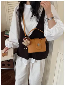 Yellow pebbled leather crossbody bag detail with cute bear plush pendant and metal lock.