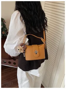 Amber yellow bucket bag detail showcasing lychee pattern texture and cute bear pendant.