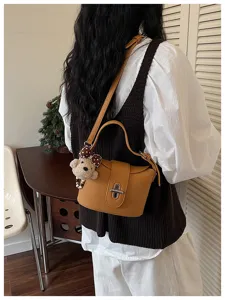 Stylish women's leather bucket bag with cute bear charm, versatile crossbody and shoulder use.