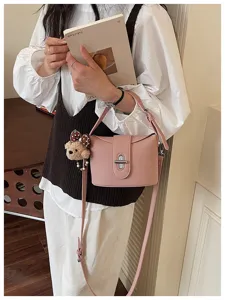 Detailed view of the chic pink litchi grain bucket bag featuring a cute plush bear charm.