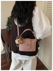 Details of trendy niche design women bucket bag with cute bear charm and crossbody strap.