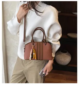 Stylish brown women's crossbody handbag with elegant vertical stripes and cute wooden bead charms.