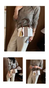 Detail view of women commuter handbag with vertical stripes and wooden bead charm for daily wear.