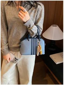 Denim contrast handbag detail showcasing stylish commuting design and delicate wooden bead charms.