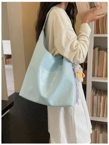 Detailed shot of a light blue slouchy hobo shoulder bag worn by a model in a cozy library setting.