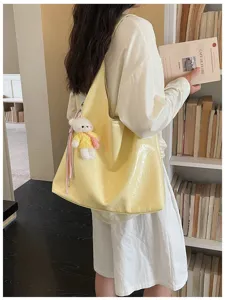 Yellow soft leather tote bag with cute bear pendant, stylish minimalist commuter shoulder bag.