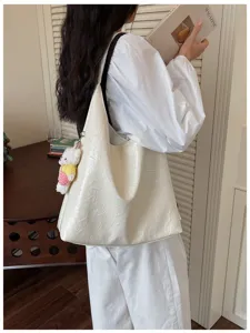 Detailed view of white soft leather shoulder bag with cute plush bear pendant and strap.