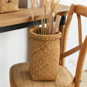 Natural woven storage basket and plant pot cover, handmade straw cylinder bin for home decor.