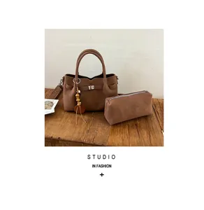 Braune Tote-Tasche und Etui Detailansicht mit rustikaler Holztischplatte und schickem Anhänger.
