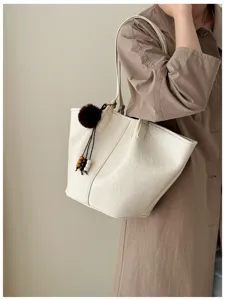 White oil wax leather tote bag detail, featuring fluffy pom-pom and wooden bead charms.