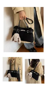 Detailansicht der stilvollen schwarzen Wildleder-Handtasche mit Metallverschluss und Plüschhasen.