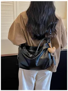 Detail view of a stylish black oil wax leather shoulder bag for women, featuring hobo style.