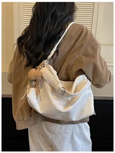 White slouchy oil-wax leather shoulder bag detail with cute knit heart charm for daily commute.