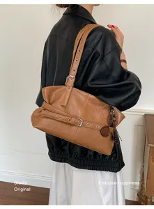 Vue de détail d'un sac porté épaule rétro en cuir marron avec boucles et lanières.