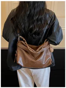 Detail shot showing the stylish brown oil-wax leather shoulder bag worn on model back.