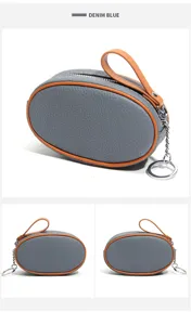 Detail view of gray leather coin purse with orange contrast piping, zipper and key ring.