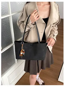 Schwarze Steinstruktur Shopper Detailansicht mit zwei Tragegriffen und Holzperlen Quaste.