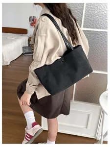 Detailansicht einer Szene mit Frau und schwarzer Kroko-Muster-Schultertasche im Alltag.