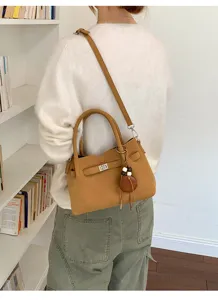 Detailansicht der stilvollen braunen Handtasche mit Metallverschluss und schickem Quastenanhänger.