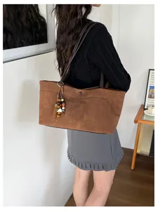 Detailansicht der braunen Vintage Kroko-Muster Tote Tasche mit Perlen Quasten Anhänger.