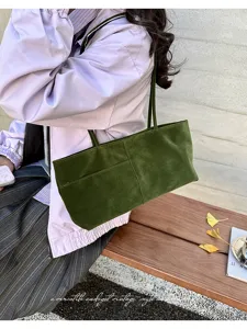Nahaufnahme der eleganten grünen Samtumhängetasche mit schmalem Riemen und Vordertasche.