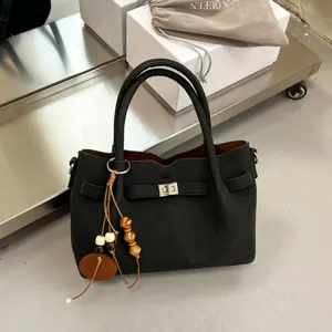 Schwarze Damen Handtasche mit Metallschnalle und Perlenanhänger für Alltag und Retro Mode.
