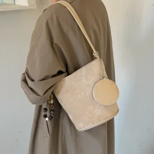 Chic beige suede bucket bag with shoulder strap and mini round pouch for women autumn fashion.