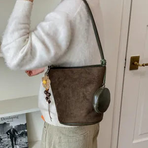 Stylish retro brown suede bucket bag for women, featuring chic shoulder strap and cute pendants.