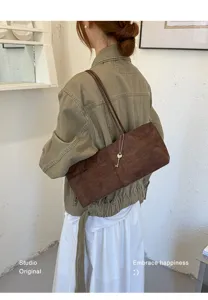 Detail view of stylish brown suede shoulder underarm bag, chic Korean commuter style.