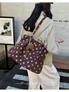 Vista detallada de un elegante bolso tote de ante marrón con un bonito colgante decorativo.