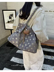 Vista detallada del bolso tote de ante gris con lunares y dije de corazón, elegante bolso casual.