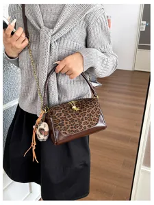 Leopard print shoulder bag detail with chain strap and fluffy charm, stylish item.