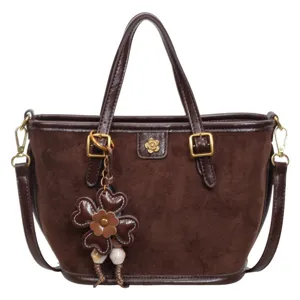Retro brown suede bucket bag for women, chic commuting shoulder and crossbody handbag with flower charm.